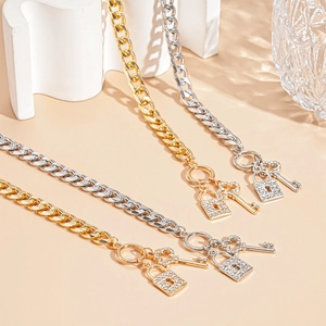 Detail of gold and silver chunky chain jewelry with rhinestone lock and key charms
