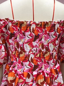 Detalle de vestido boho con estampado floral, nido de abeja y tirantes rojos