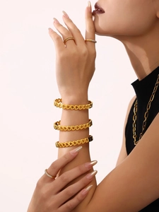 Detail of hollow heart link bracelet in 18K gold plating styled with stacked rings