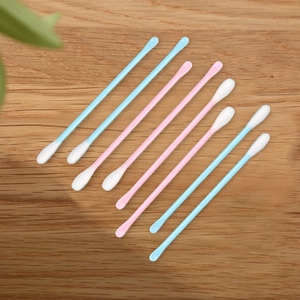 Close-up of colorful double-headed cotton swabs with plastic stems on a wooden background