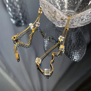 Detail of gold titanium cube necklace showing lobster clasp and adjustable chain on glass