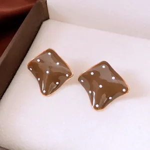 Retro caramel square polka dot earrings with golden edges on white jewelry box