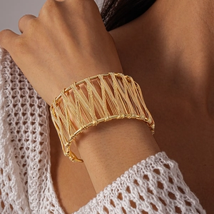 Close-up of golden wide mesh cuff bracelet on wrist with elegant knit sleeve detail