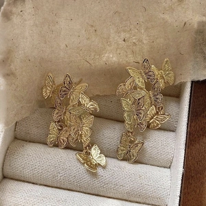 Detailed view of layered gold butterfly earrings displayed in a luxury jewelry box
