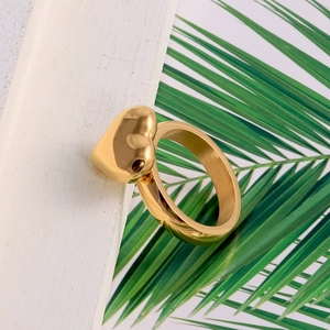 Detailed view of a golden heart-shaped stainless steel ring on a white wooden frame