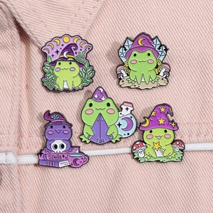 Vue détaillée des épingles émaillées grenouille magicienne sur fond en denim rose