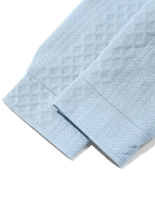 Detail of light blue knit shirt cuff with diamond jacquard pattern and neat stitching
