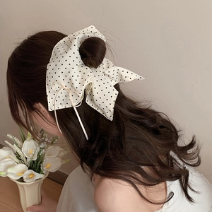 French bow hair tie with black polka dots on cream fabric shown on person back