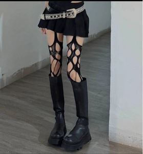 Detail of black distressed fishnet stockings with irregular holes in punk gothic style