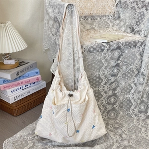 Dettaglio dei fiocchi colorati ricamati sulla borsa a spalla in tela beige a quadretti