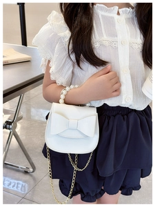 Close-up of kids white mini purse featuring a large bow and pearl beaded handle