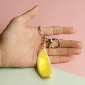 Handheld realistic yellow lemon slice keychain with silver metal ring and clasp detail