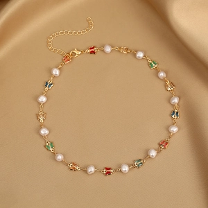 Detail of golden butterfly and baroque pearl necklace on elegant gold silk fabric