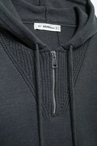 Detail of dark grey hoodie with rib-knit fabric, silver half-zipper and drawstring