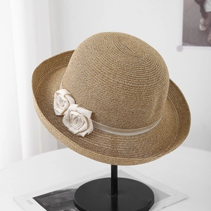 Gros plan d'un chapeau de soleil en paille avec ruban champagne et fleurs en tissu
