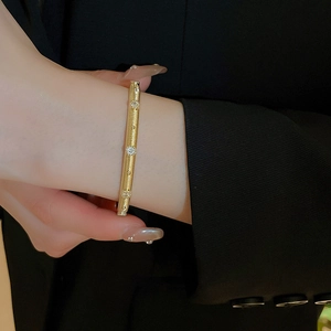Detail of vintage gold-plated zircon bangle showing the brushed metal texture and gemstones