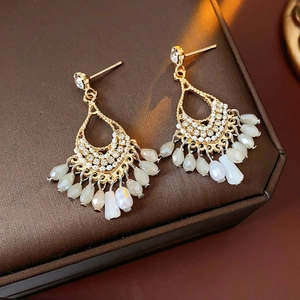 Macro detail of Bohemian drop earrings with white beads and crystal rhinestones