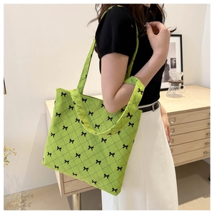 Dettaglio della borsa shopper verde trapuntata con motivo a fiocco nero e tracolla larga
