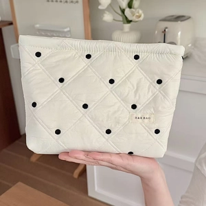 Gros plan sur la trousse de maquillage matelassée blanche à pois avec étiquette de marque
