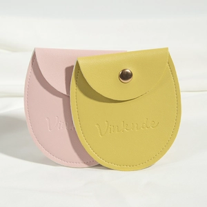 Pink and yellow PU leather jewelry pouches with snap buttons on white fabric