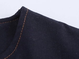 Macro shot of dark navy fabric texture with contrasting orange topstitching detail