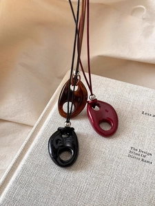 Detailed view of resin oval pendant necklaces in black, red, and amber tortoiseshell textures
