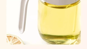 Detail of a leakproof glass oil sprayer bottle with ergonomic white handle and lemon decor