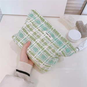 Detail of green and white tweed makeup bag featuring simple wish woven label and zipper