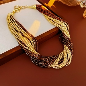 Close-up of multilayer beaded necklace with twisted gold and brown beads and T-bar clasp