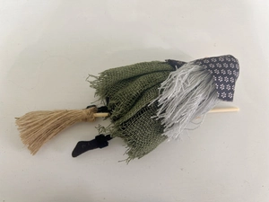 Detail of a handmade witch doll in green burlap skirt riding a wooden broomstick for Halloween