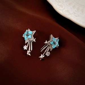 Elegant silver star earrings with light blue zircon stones on a dark fabric background