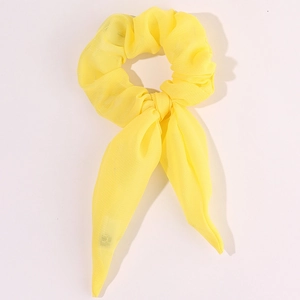 Detail of a bright yellow chiffon scrunchie with long ribbons and a bow tie design