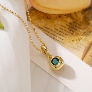 Gold plated ball necklace with green zircon pendant on elegant vintage paper background