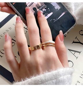 Detail of gold-plated rings with crinkled texture and mother of pearl inlay on hand