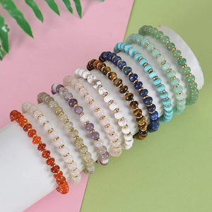 Colorful natural stone beaded bracelets with golden spacers displayed on a white stand