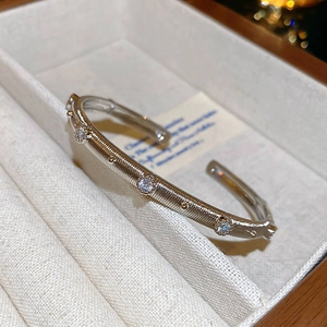 Detailed macro shot of vintage brushed gold open bangle with floral zircon inlay details