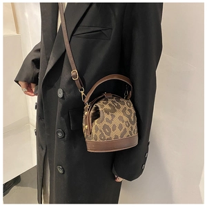 Brown vintage handbag with textured pattern shown as a crossbody on a black coat model