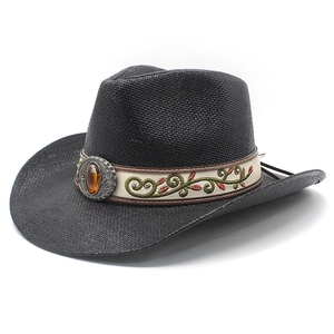 Détail d'un chapeau de cowboy en paille avec bande brodée florale et boucle en métal