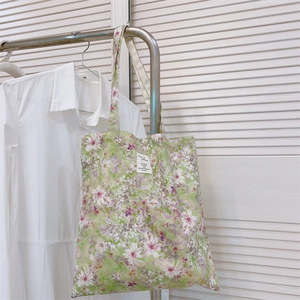 Dettaglio della borsa tote in tela a fiori verde chiaro con etichetta tessuta su camicia