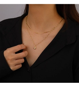 Close-up of gold layered heart lock pendant necklace on model with black background