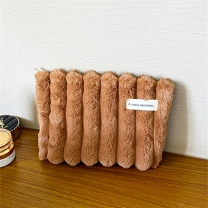 Detail of soft brown plush makeup bag with finger biscuit wavy design and brand label