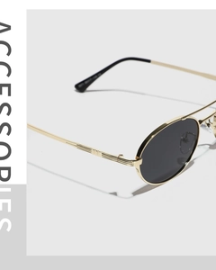 Detail of vintage oval gold metal frame sunglasses with gray lenses and ribbed hinges