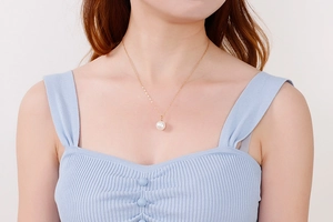 Détail du collier en acier titane doré élégant avec un grand pendentif en perle blanche