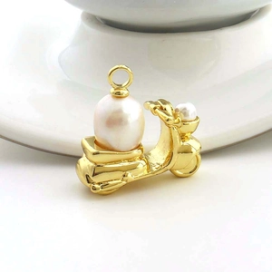 Macro detail of golden motorcycle pendant with large white pearl on white ceramic