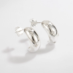 Macro detail of S925 sterling silver hoop earrings with engraved star and zircon