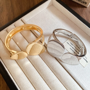 Close-up of gold and silver irregular oval double-layer bracelets on a beige jewelry tray