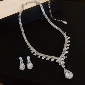 Macro detail of teardrop zircon necklace and earrings set on black background