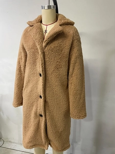 Detailed view of camel faux fur texture and black buttons on a long teddy coat