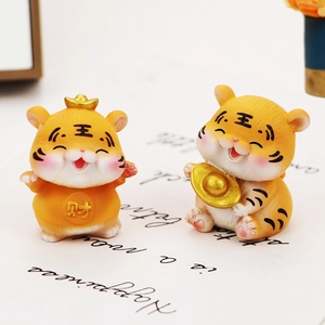 Close-up of resin tiger figurines with gold ingots and fortune characters for car decor
