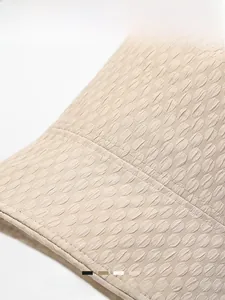 Detail of beige bucket hat showing hexagonal quilted texture and reinforced stitching
